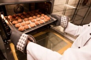 a-person-taking-pastries-out-of-an-oven