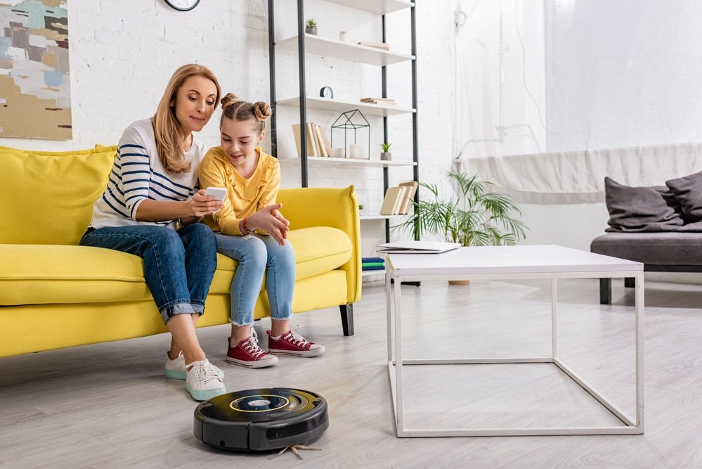 The mother demonstrates to her daughter how to use her smartphone to control the robotic cleaner