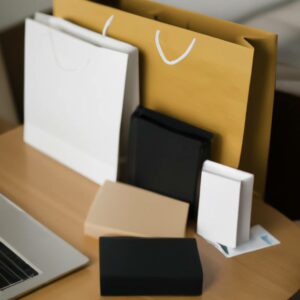 Shopping bags of different sizes and colors placed on a table next to a laptop