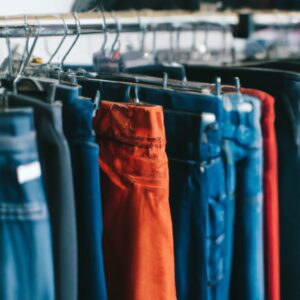 Up-close image of shorts and pants hanging on racks inside a thrift shop